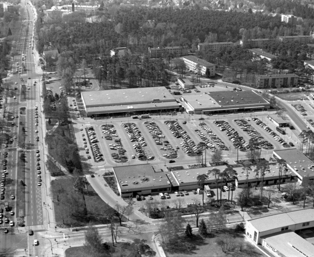Luftaufnahme vom Einkaufszentrum Truman Plaza mit einem großen Parkplatz und vielen Autos