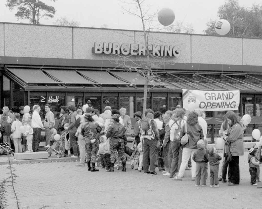Menschen stehen am Eröffnungstag vor dem Gebäude von Burger King Schlange.