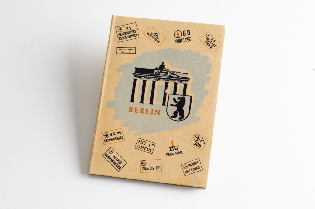 Titelseite einer Broschüre mit Zeichnungen vom Brandenburger Tor und dem Berliner Wappen in der Mitte sowie Stempelabdrücken von Einrichtungen der amerikanischen Besatzungsbehörden