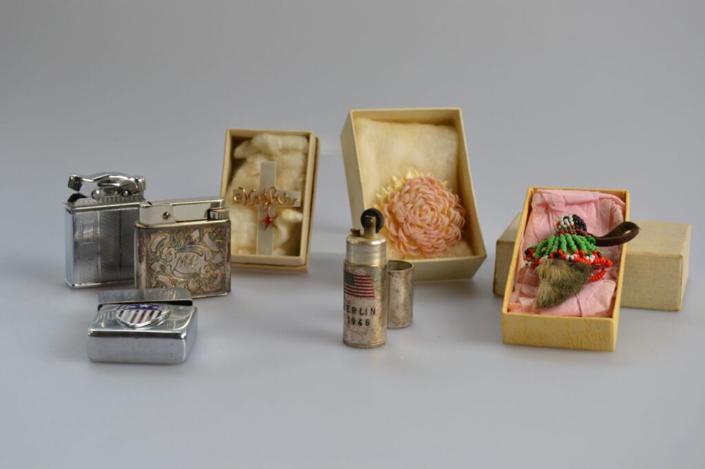 Three cigarette lighters, three small boxes with pins and brooches 