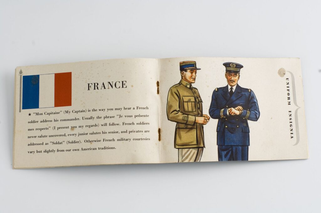 Brochure ouverte avec texte anglais, drapeau français et dessin de deux soldats en uniforme